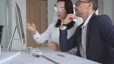 Profesyonel mimar takımı bilgisayar ekranında inşaat projesi planları ve mimari çizimleri tartışıyor. İş ve mimari kavramı