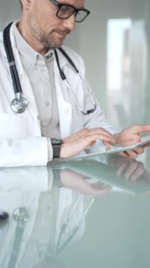 Steteskop takan profesyonel bir doktor, modern bir ofiste sağlık hizmetleri veri yönetimi ve teşhisi için dijital tablet kullanıyor. Tıp, sağlık ve bilim konsepti