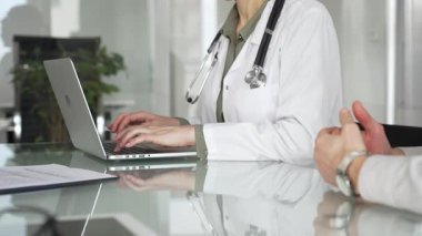 Bir hastane ofisinde dizüstü bilgisayar kullanarak hastalara sağlık sigortasını online danışma sırasında açıklayan bir tıbbi uzman. Tıp, sağlık ve bilim konsepti