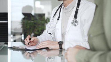 Doktorlar, bir sağlık kliniğinde ya da hastane ofisinde bir hastaya danışmanlık yaparken panoya notlar yazarlar. Tıp, sağlık ve bilim konsepti