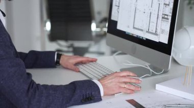 Bilgisayarda çalışan bir mimar, klavyede yazı yazan eller, yeni inşaat için kat planları ve mühendislik planları geliştiren bir mimar. İş ve mimari kavramı