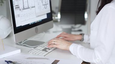 Kadın mimarların elleri klavyede yazı yazıyor, fareyi manipüle ediyor, mühendislik ve kentsel planlama için dijital planlar üzerinde çalışıyor. İş ve mimari kavramı
