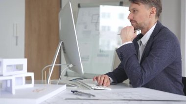 Bina tasarımı ve planlama üzerine odaklanan profesyonel mimar, bir bilgisayar ve fiziksel modelin planlarıyla çalışıyor. İş ve mimari kavramı