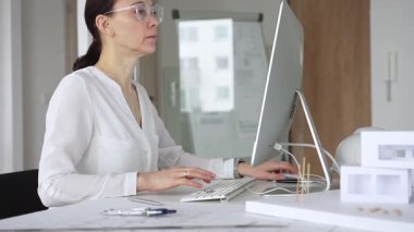 Profesyonel kadın, ofis çalışma alanındaki masasında teknoloji ve fiziksel modeller kullanarak mimari tasarımlar yaratmaya odaklandı. İş ve mimari kavramı