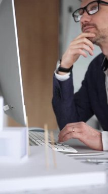 Profesyonel mimar, bir masada oturmuş proje geliştirmeyi düşünürken planlar ve tasarım planlarını analiz ediyor. İş ve mimari kavramı