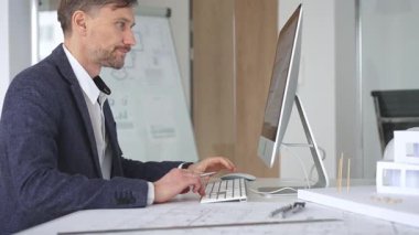 Erkek mimar ekranda dijital planları ve mimari çizimleri inceleyerek tasarım ve inşaat projesi yaratıyor. İş ve mimari kavramı