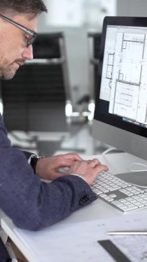 Modern ofiste klavyede yazan profesyonel mimar, planlar, ölçek modelleri ve tasarım araçları ile çevrili, planlama projesi. İş ve mimari kavramı