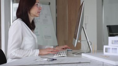 Bilgisayarda çalışan kadın mimar, yeni mimari projeler tasarlıyor, inşaat ve emlak gelişimini düşünüyor. İş ve mimari kavramı
