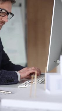 Erkek mimar, mimari bir stüdyoda yeni yapılar ve modeller tasarlayarak bilgisayar ekranına ve planlara derinden odaklanmıştır. İş ve mimari kavramı