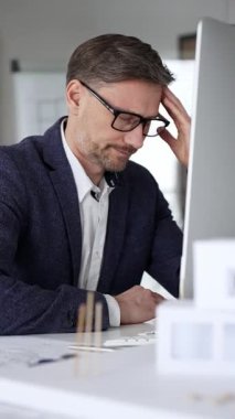 Profesyonel mimar, bir masada oturmuş proje geliştirmeyi düşünürken planlar ve tasarım planlarını analiz ediyor. İş ve mimari kavramı