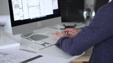 Bilgisayarda çalışan bir mimar, klavyede yazı yazan eller, yeni inşaat için kat planları ve mühendislik planları geliştiren bir mimar. İş ve mimari kavramı