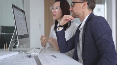 Profesyonel mimar takımı bilgisayar ekranında inşaat projesi planları ve mimari çizimleri tartışıyor. İş ve mimari kavramı