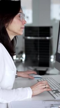 Profesyonel mimar kadın bilgisayar klavyesinde daktilo kullanıyor, planlara ve masadaki tasarım araçlarına nezaret ediyor, yeni mimari planlar yapıyor. İş ve mimari kavramı