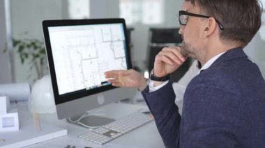 Mimarlar ve mühendisler birlikte çalışarak modern bir masaüstü bilgisayar ekranının planlarını tartışıyorlar. Takım çalışması ve tasarım süreci gösteriliyor. İş ve mimari kavramı