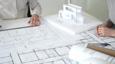 Modern mimari projesinde işbirliği yapan mimarlar, bina tasarımı, planlama, yaratıcılık ve sürdürülebilir inşaatın vurgulanması için ayrıntılı planlar ve 3D modeli gözden geçiriyorlar.