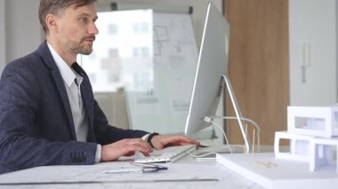 Erkek mimar ekranda dijital planları ve mimari çizimleri inceleyerek tasarım ve inşaat projesi yaratıyor. İş ve mimari kavramı