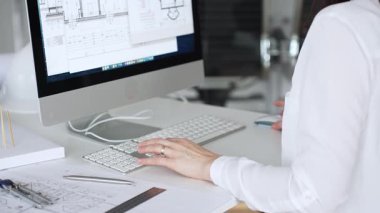 Kadın mimarların elleri klavyede yazı yazıyor, fareyi manipüle ediyor, mühendislik ve kentsel planlama için dijital planlar üzerinde çalışıyor. İş ve mimari kavramı