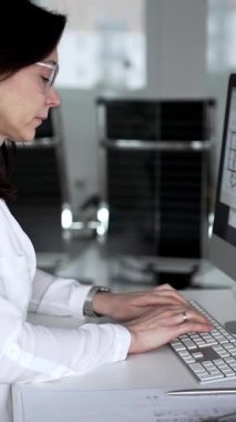 Profesyonel mimar kadın bilgisayar klavyesinde daktilo kullanıyor, planlara ve masadaki tasarım araçlarına nezaret ediyor, yeni mimari planlar yapıyor. İş ve mimari kavramı