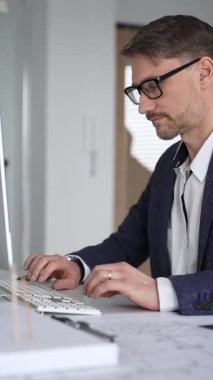 Planlar ve mimari model üzerinde çalışan mimar, ofisteki bilgisayar yazılımını kullanarak yeni bir bina projesi planlıyor. İş ve mimari kavramı