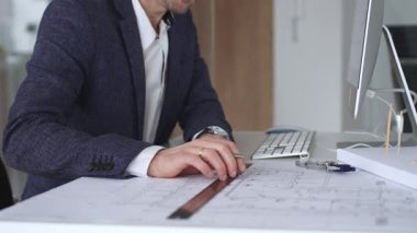 Yeni bina planları üzerinde çalışan mimar, ayrıntılı tasarım ve mühendislik projeleri geliştirmek için bir pusula ve bilgisayar kullanıyor. İş ve mimari kavramı