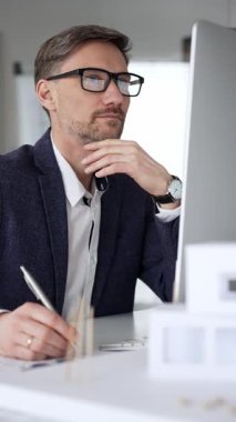 Profesyonel mimar, bir masada oturmuş proje geliştirmeyi düşünürken planlar ve tasarım planlarını analiz ediyor. İş ve mimari kavramı