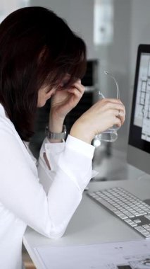 Bilgisayar ve mimari modeller üzerinde çalışırken kendini yorgun hisseden ve ofis stresi, baş ağrısı ve göz yorgunluğu yüzünden burun köprüsünü ovuşturan bir kadın. İş ve mimari kavramı