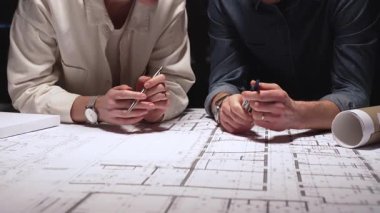 Mimarlık uzmanları teknik planları analiz ediyor ve yeni bir şehir gelişimi tasarlamak için taslak araçları kullanıyorlar. Yakınlardaki ölçekli bir modelle inşaat planlama ve mühendislik tasarımına odaklanıyor.