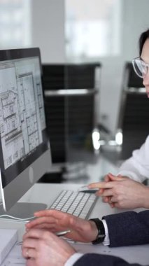 Dijital ve fiziksel yapı planlarını inceleyerek, mimari tasarım projesinde işbirliği yapan mühendislik uzmanları. İş adamları ve mimari konsepti