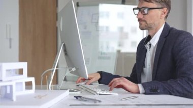 Profesyonel mimar, kaba yazılım ve fiziksel ölçekte bir model kullanarak yeni bir yapı projesi tasarlıyor. Planlarla dolu bir masada çalışıyorum. İş ve mimari kavramı