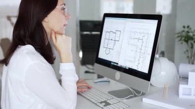 Ev planında çalışan ve masaüstü bilgisayarında tasarım yapan kadın mimar mimari bir proje geliştiriyor. İş ve mimari kavramı