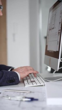 Erkek mimar, mimari bir stüdyoda yeni yapılar ve modeller tasarlayarak bilgisayar ekranına ve planlara derinden odaklanmıştır. İş ve mimari kavramı