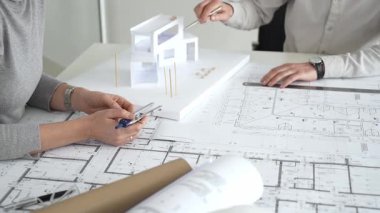 Modern mimari projesinde işbirliği yapan mimarlar, bina tasarımı, planlama, yaratıcılık ve sürdürülebilir inşaatın vurgulanması için ayrıntılı planlar ve 3D modeli gözden geçiriyorlar.