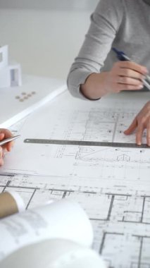 Mimarlar planları ve mimari modelleri inceliyor, profesyonel bir ofis toplantısında tasarım ve şehir planlamasını tartışıyor, gelecekteki inşaat projeleri üzerinde işbirliği yapıyor, kapatıyorlar.