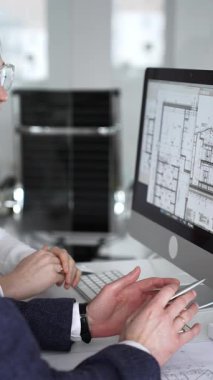 Dijital ve fiziksel yapı planlarını inceleyerek, mimari tasarım projesinde işbirliği yapan mühendislik uzmanları. İş adamları ve mimari konsepti