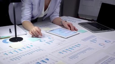 Ekonomik raporları ve hesap tablolarını bir masada inceleyen, stratejik planlama ve yatırım kararları için notlar alırken çizelgeleri ve dizüstü bilgisayarların grafiklerini analiz eden iş adamı.