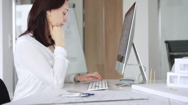 Ev planında çalışan ve masaüstü bilgisayarında tasarım yapan kadın mimar mimari bir proje geliştiriyor. İş ve mimari kavramı