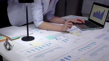 Finans raporlarını, çizelgeleri ve hesap tablolarını beyaz bir masada inceleyen, not alan bir iş adamı, bütçe, planlama ve analitik kararlar için bir bar grafiği gösterirken,