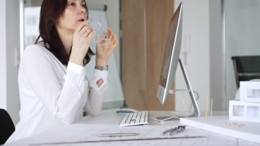 Bilgisayar ve mimari modeller üzerinde çalışırken kendini yorgun hisseden ve ofis stresi, baş ağrısı ve göz yorgunluğu yüzünden burun köprüsünü ovuşturan bir kadın. İş ve mimari kavramı