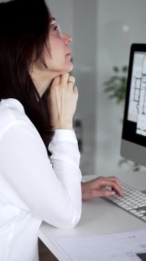 Mimari proje planlayan kadın, planlar ve bilgisayar üzerinde çalışıyor. Modern mimarlık bürosu