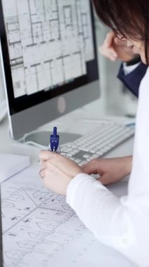 Dijital ve fiziksel yapı planlarını inceleyerek, mimari tasarım projesinde işbirliği yapan mühendislik uzmanları. İş adamları ve mimari konsepti