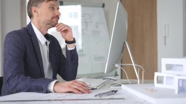 Bina tasarımı ve planlama üzerine odaklanan profesyonel mimar, bir bilgisayar ve fiziksel modelin planlarıyla çalışıyor. İş ve mimari kavramı