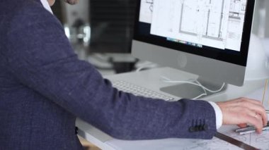 Bilgisayarda çalışan bir mimar, klavyede yazı yazan eller, yeni inşaat için kat planları ve mühendislik planları geliştiren bir mimar. İş ve mimari kavramı