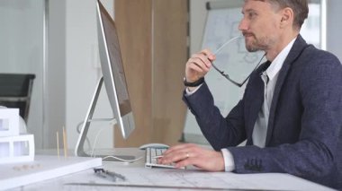 Bina tasarımı ve planlama üzerine odaklanan profesyonel mimar, bir bilgisayar ve fiziksel modelin planlarıyla çalışıyor. İş ve mimari kavramı