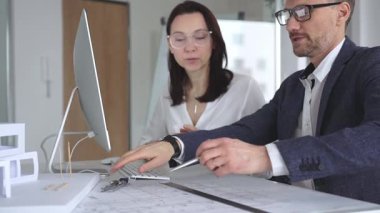 Profesyonel mimar takımı bilgisayar ekranında inşaat projesi planları ve mimari çizimleri tartışıyor. İş ve mimari kavramı