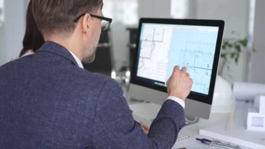 Mimarlar ve mühendisler birlikte çalışarak modern bir masaüstü bilgisayar ekranının planlarını tartışıyorlar. Takım çalışması ve tasarım süreci gösteriliyor. İş ve mimari kavramı