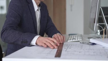 Yeni bina planları üzerinde çalışan mimar, ayrıntılı tasarım ve mühendislik projeleri geliştirmek için bir pusula ve bilgisayar kullanıyor. İş ve mimari kavramı