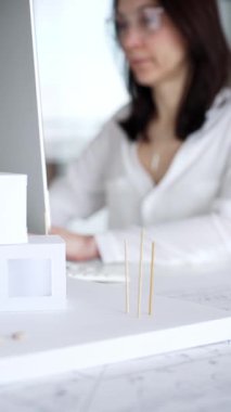 Modern ofis masasında mimari modeller ve inşaat planları tasarlayan, bilgisayar klavyesinde yazan bir mimar. İş ve mimari kavramı