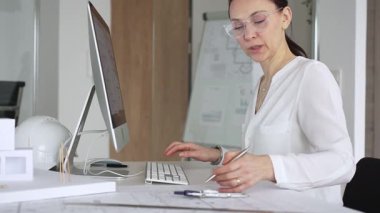 Profesyonel kadın, ofis çalışma alanındaki masasında teknoloji ve fiziksel modeller kullanarak mimari tasarımlar yaratmaya odaklandı. İş ve mimari kavramı