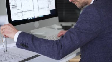 Bilgisayarda çalışan bir mimar, klavyede yazı yazan eller, yeni inşaat için kat planları ve mühendislik planları geliştiren bir mimar. İş ve mimari kavramı