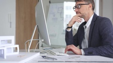 Bina tasarımı ve planlama üzerine odaklanan profesyonel mimar, bir bilgisayar ve fiziksel modelin planlarıyla çalışıyor. İş ve mimari kavramı